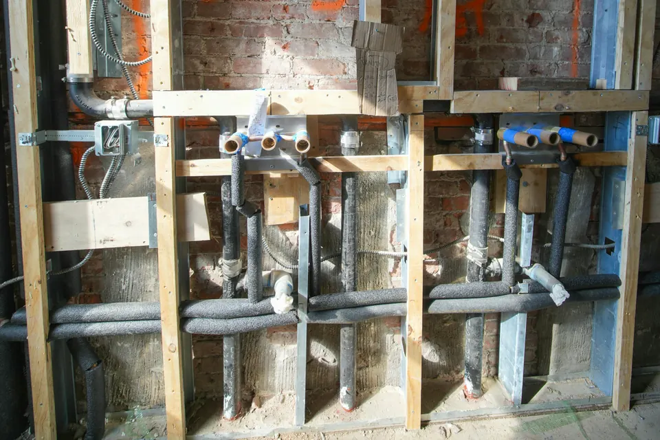New water lines and valves installed between the studs of an open wall