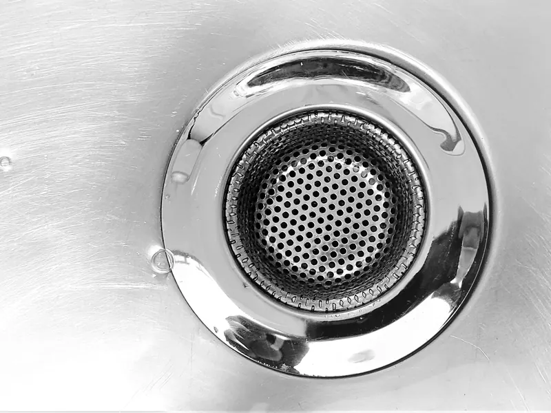 Close-up of a stainless steel kitchen sink drain and strainer